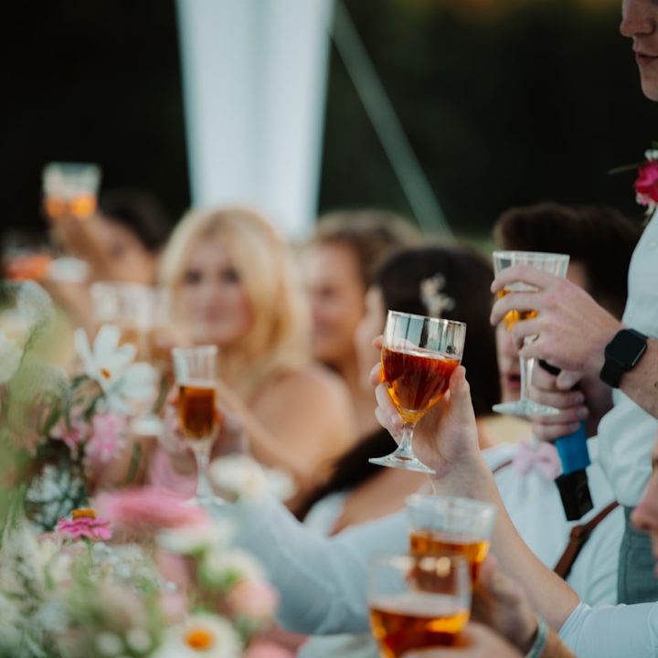 Groupe de personnes levant des verres de bières lors d'une célébration en plein air.